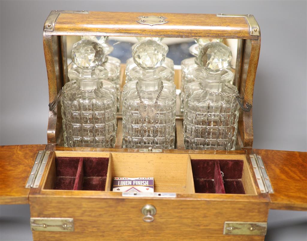 A late Victorian oak and electroplate mounted three decanter tantalus, with wine labels B, W and C